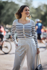 a lady in a striped square neck top and a pair of white pants